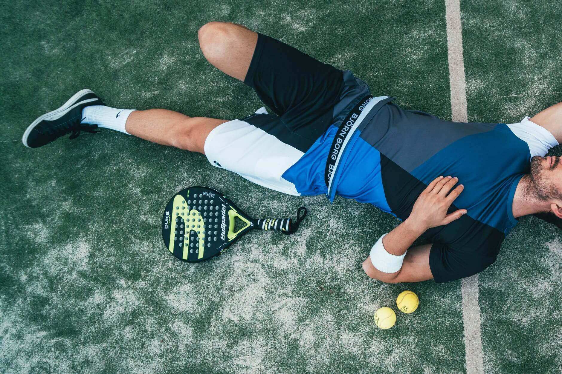 man lying beside on green tennis balls